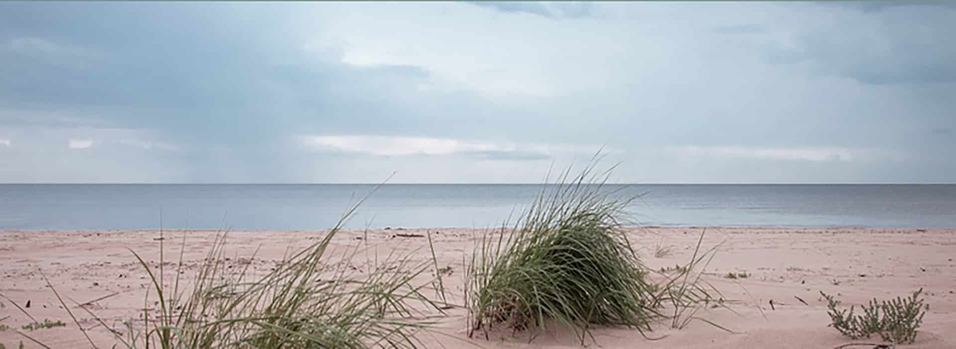 Rustig strandlandschap met duinen en horizon onder bewolkte lucht